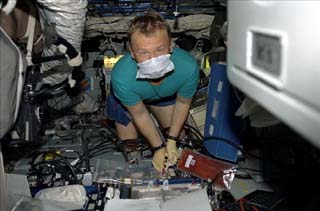 Mission Specialist Andrew Thomas, masked, sets up the Cocult experiment.